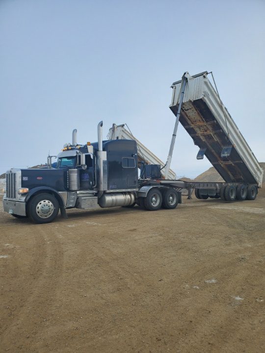 semi truck and trailer unloading gravel